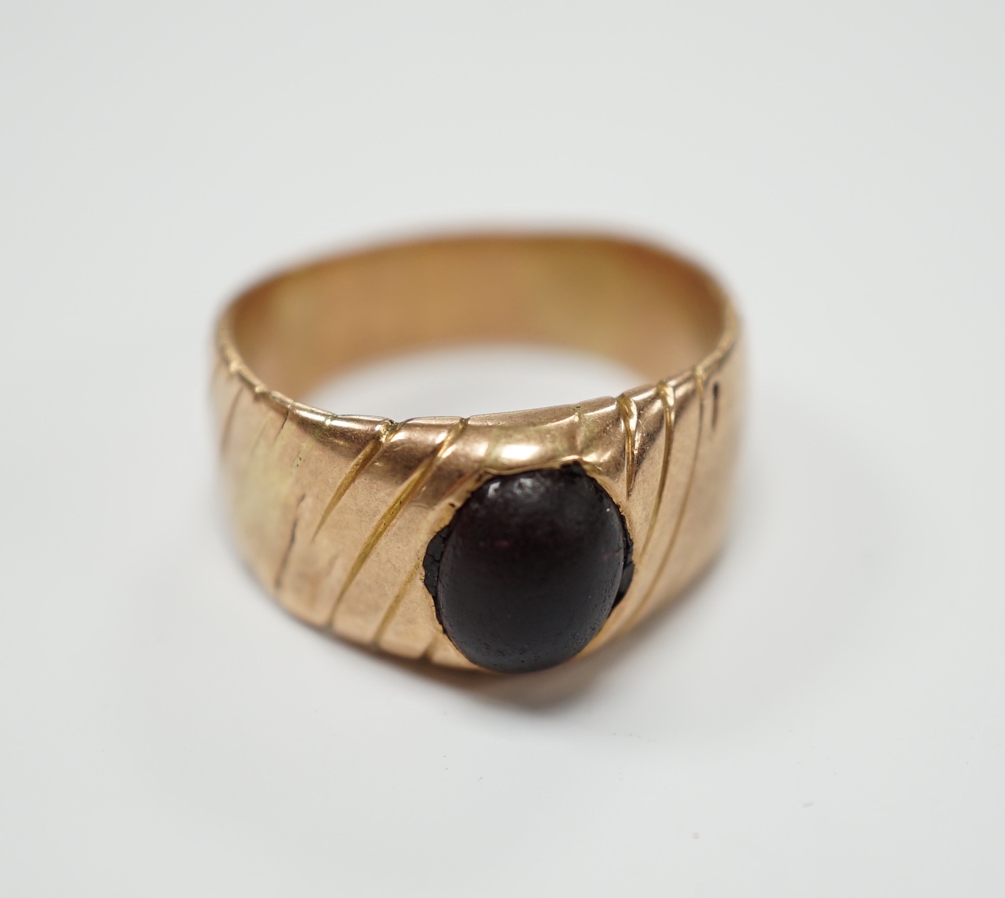 An antique engraved yellow metal and cabochon red paste set ring, size Q, gross weight 5.8 grams.